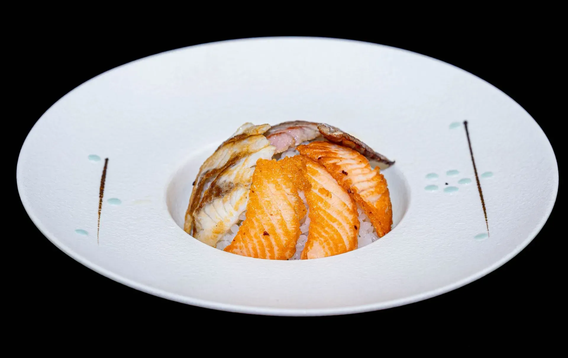 Salmone a fette con salsa, servito in un piatto ovale bianco.