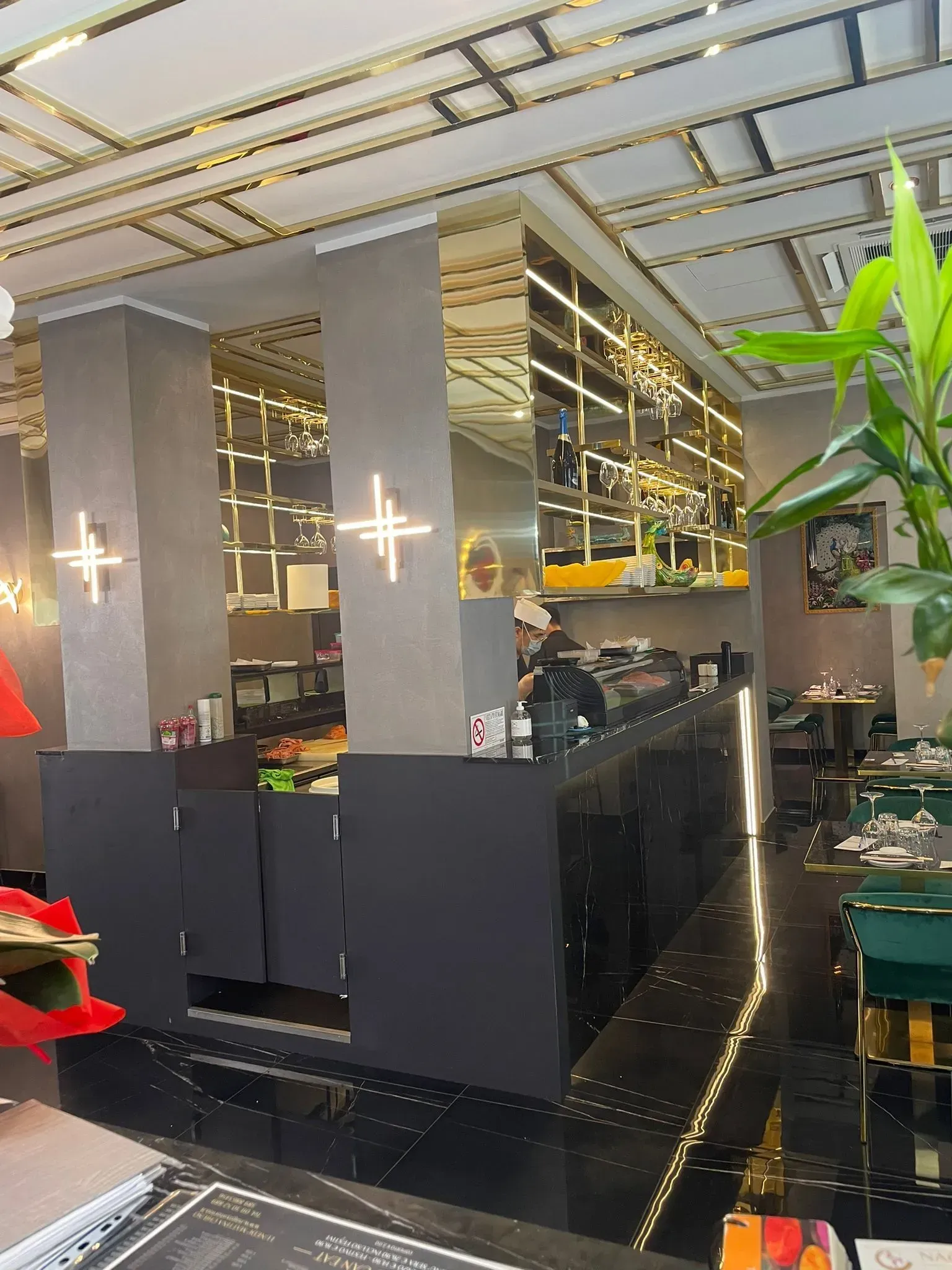 Interni moderni del ristorante con pareti a specchio, sedie nere e luci brillanti a soffitto.