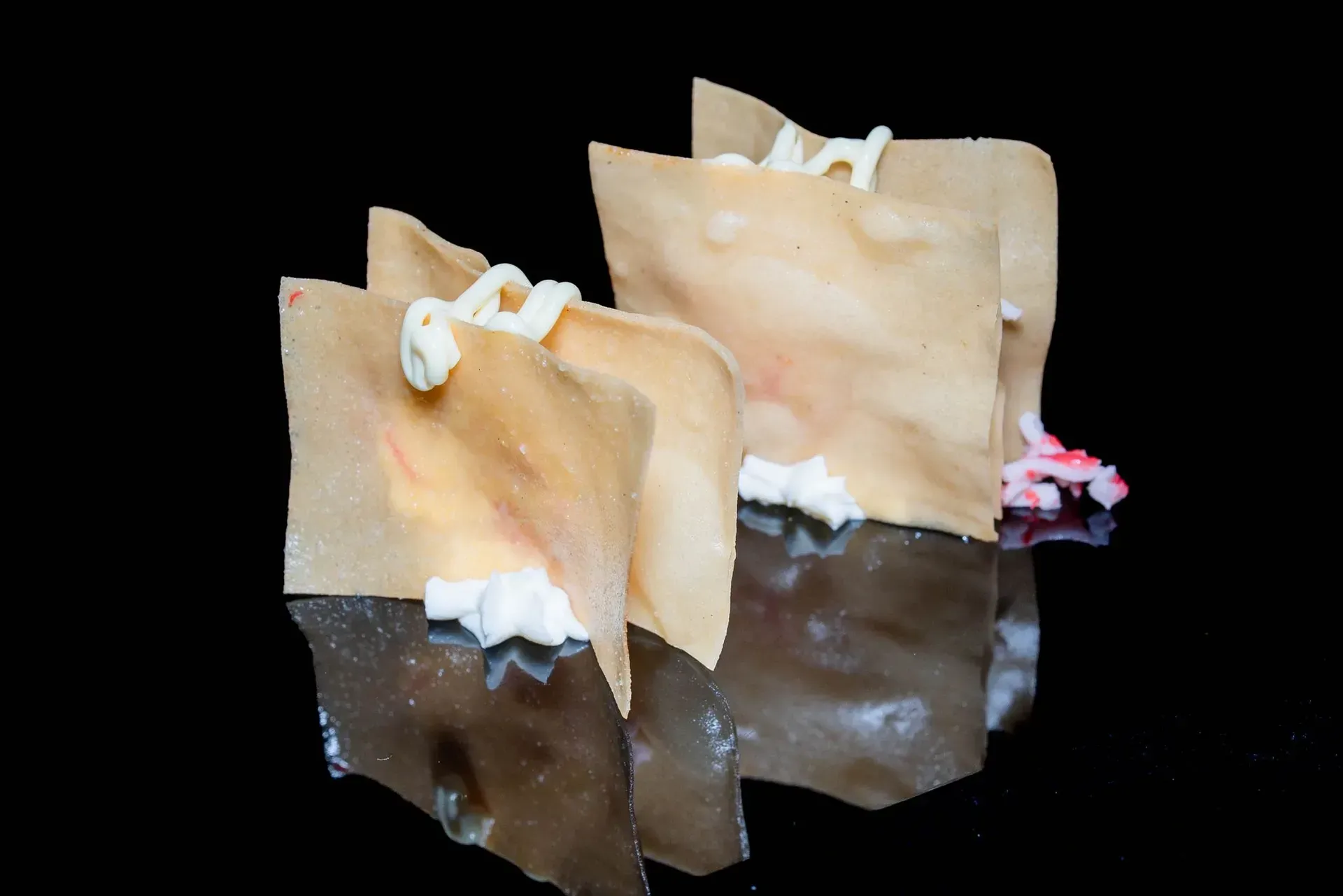 Mollette da bucato color beige agganciate a una superficie scura riflettente su sfondo nero