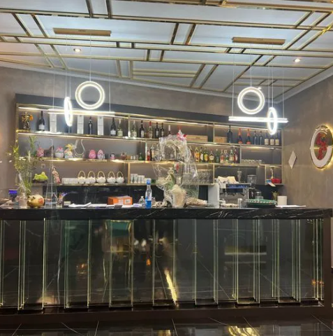 Elegante interno da bar con mensole a specchio, bicchieri e luci circolari luminose dietro un bancone scuro.