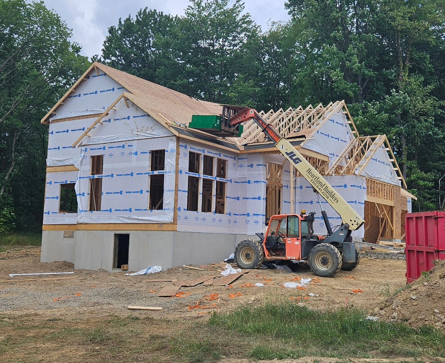 Construction of a house with a forklift placing materials on the roof.