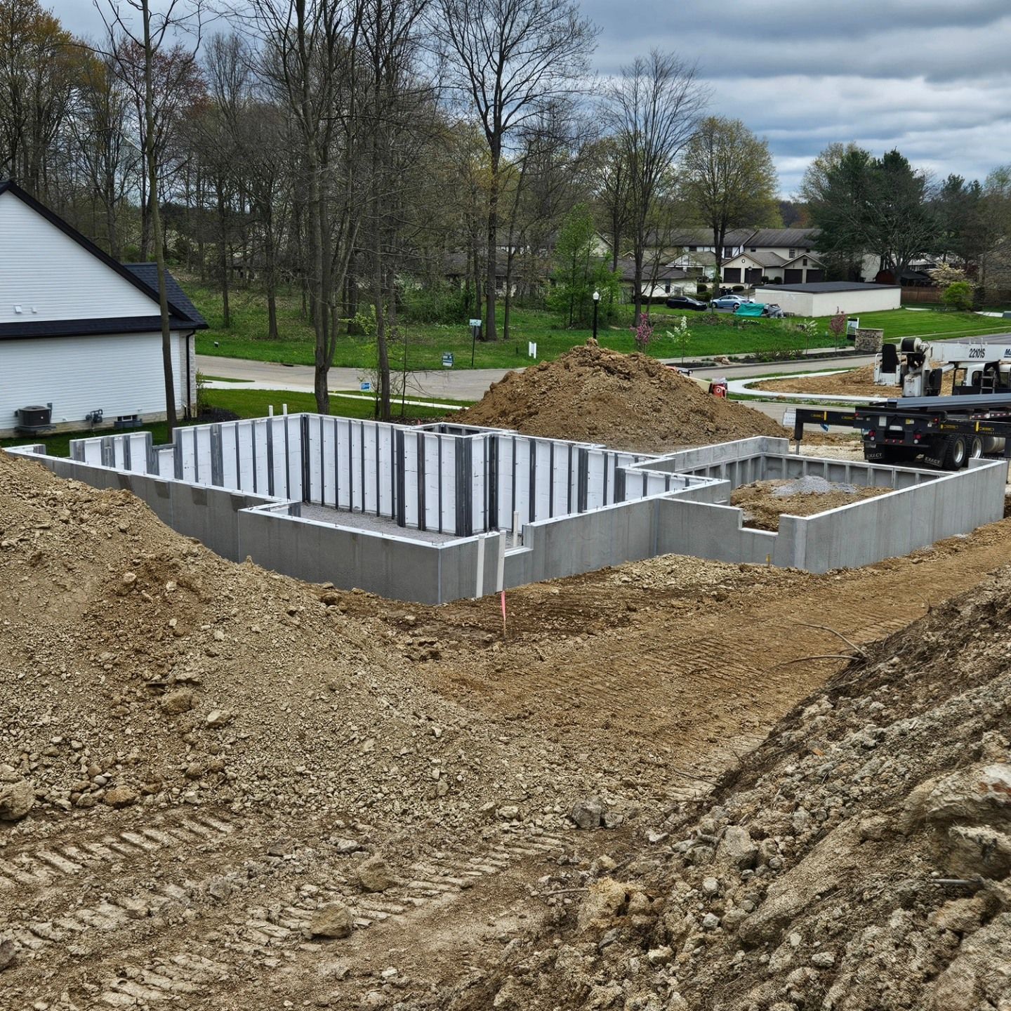 Foundation of a new house under construction; gray concrete walls and dirt.