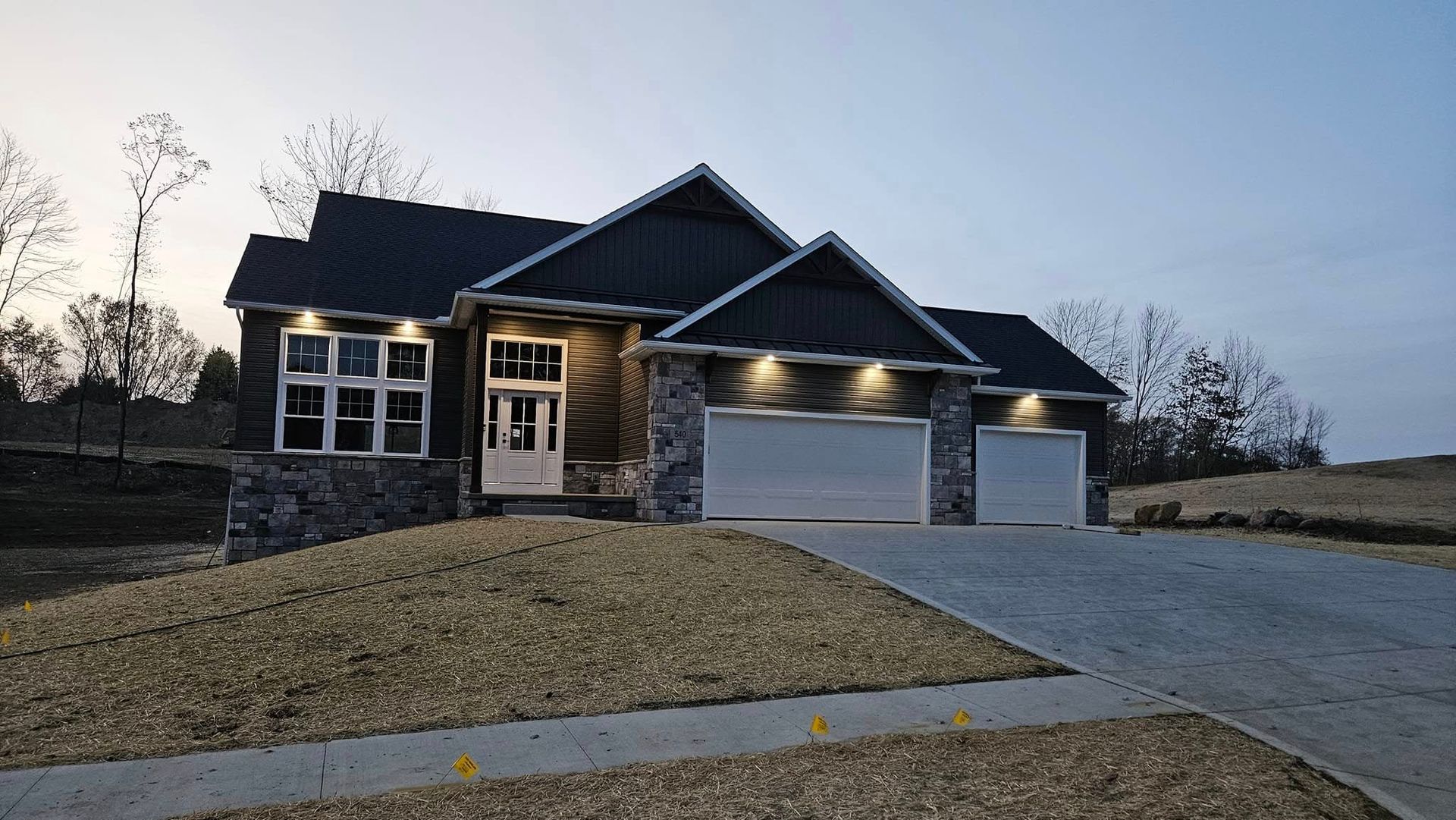 Modern house with stone accents and two-car garage. Overcast sky.