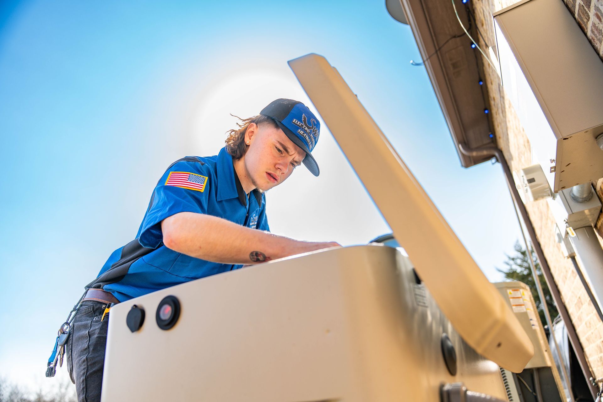 A man in a blue shirt is working on a pipe outside of a house.