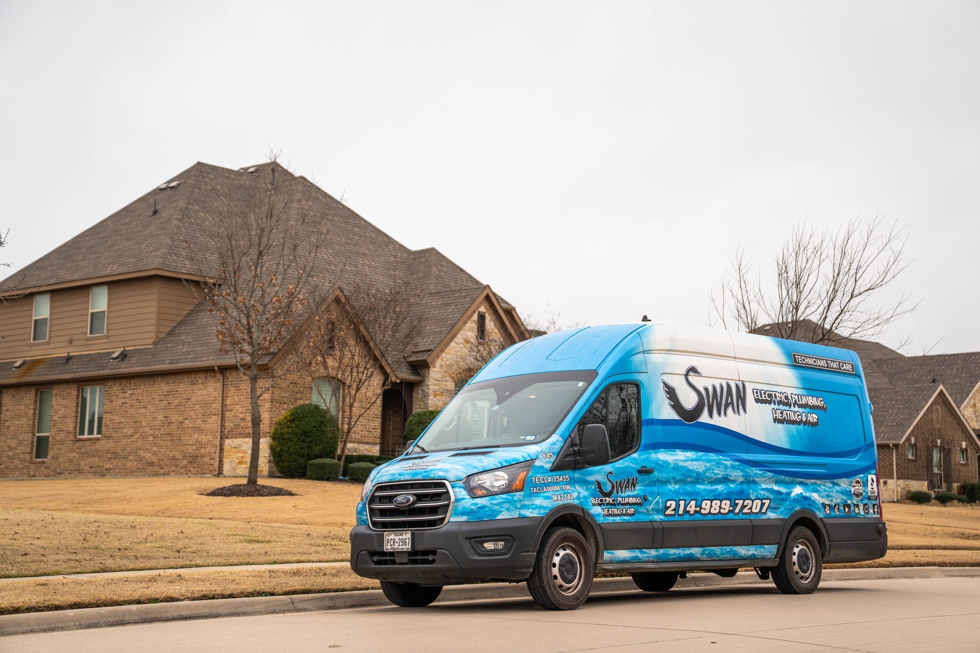 A man in a blue shirt is kneeling down next to a water heater.