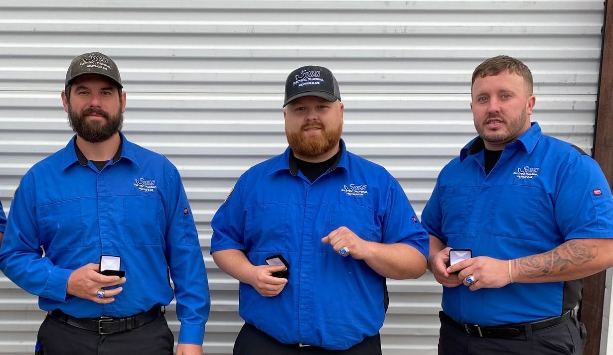 Three men in blue shirts are standing next to each other.