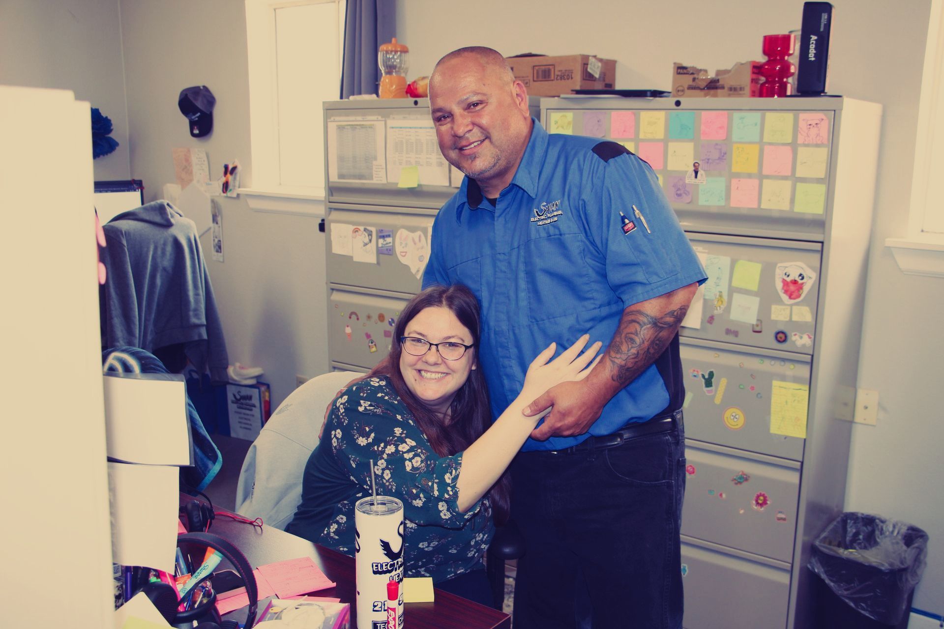 A man and a woman are posing for a picture in an office.