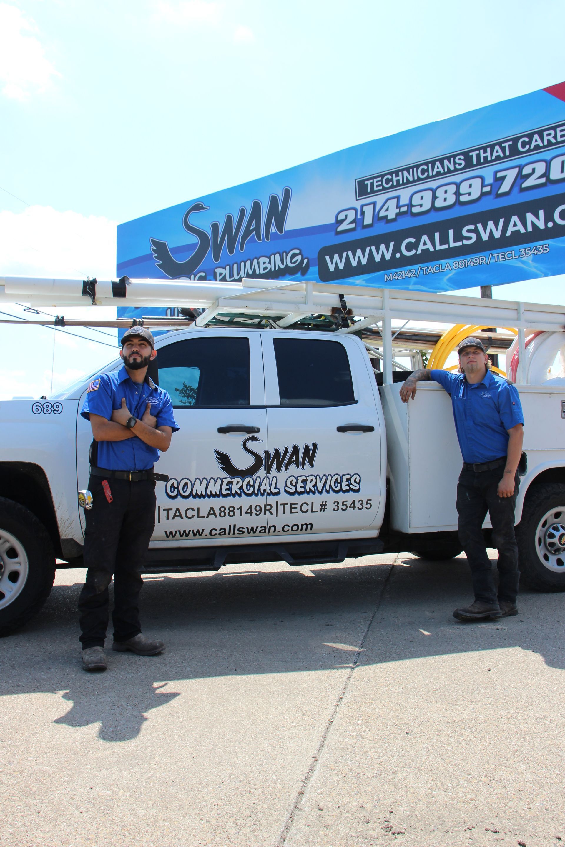 Two men are standing next to a swan plumbing truck.