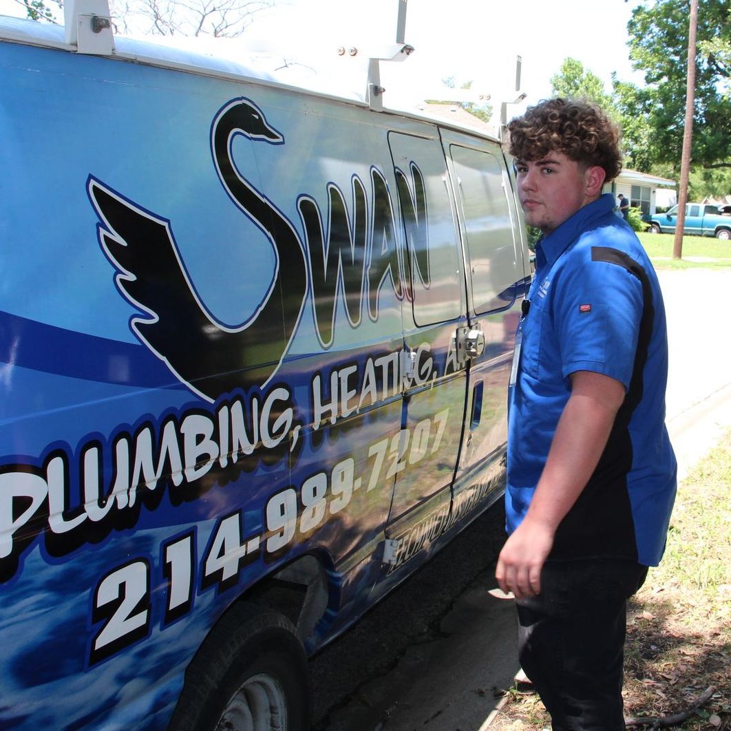 A man in a blue shirt is standing next to a plumbing van