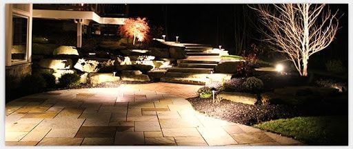 A walkway is lit up at night in front of a house.