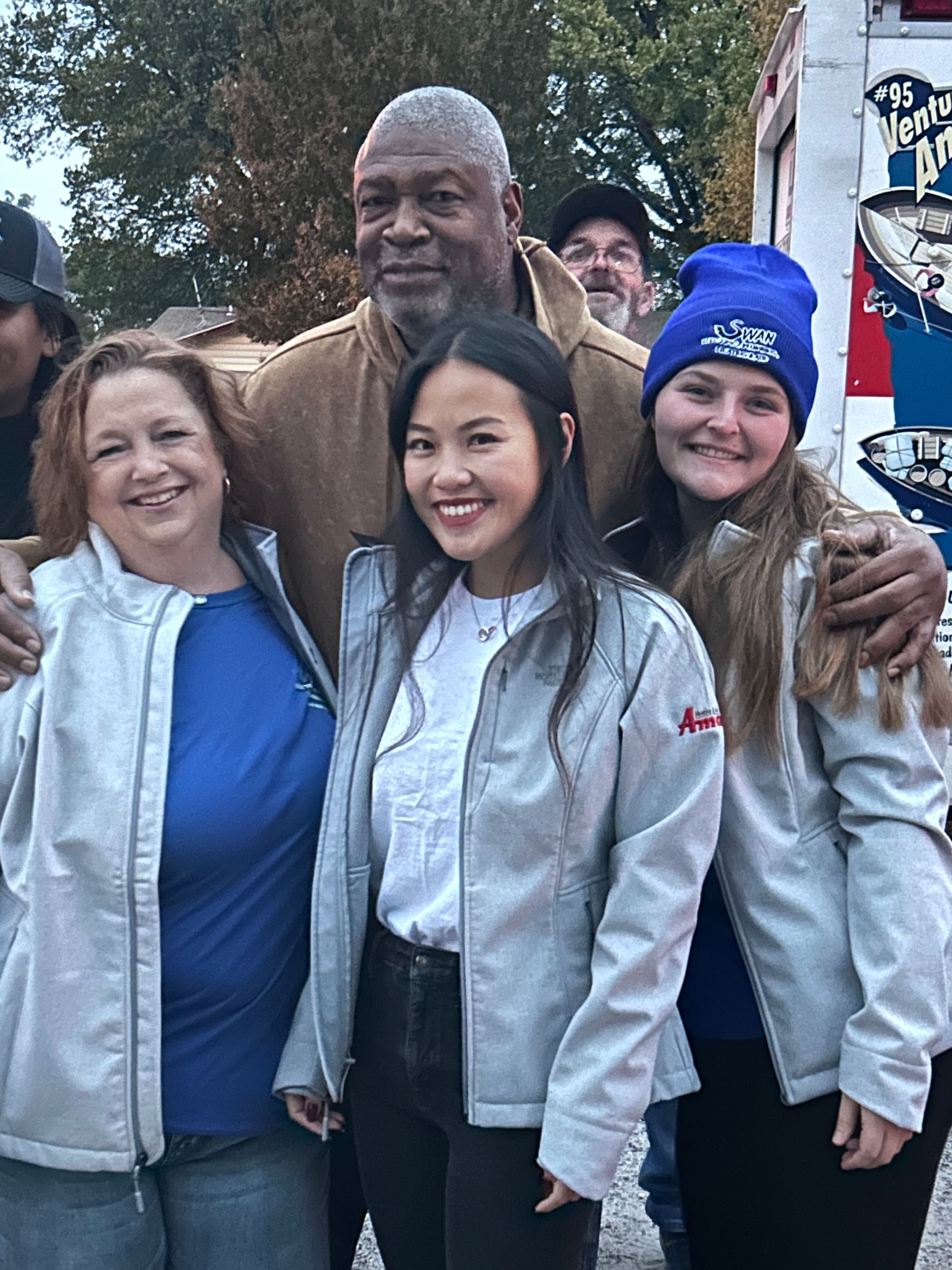 A group of people are posing for a picture in front of a food truck.