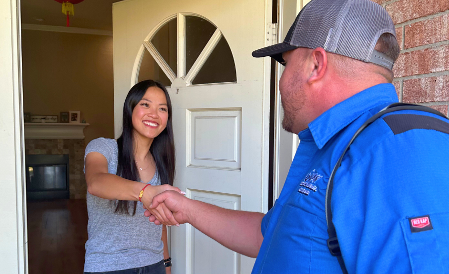 A man in a blue shirt is shaking hands with a woman in a doorway.