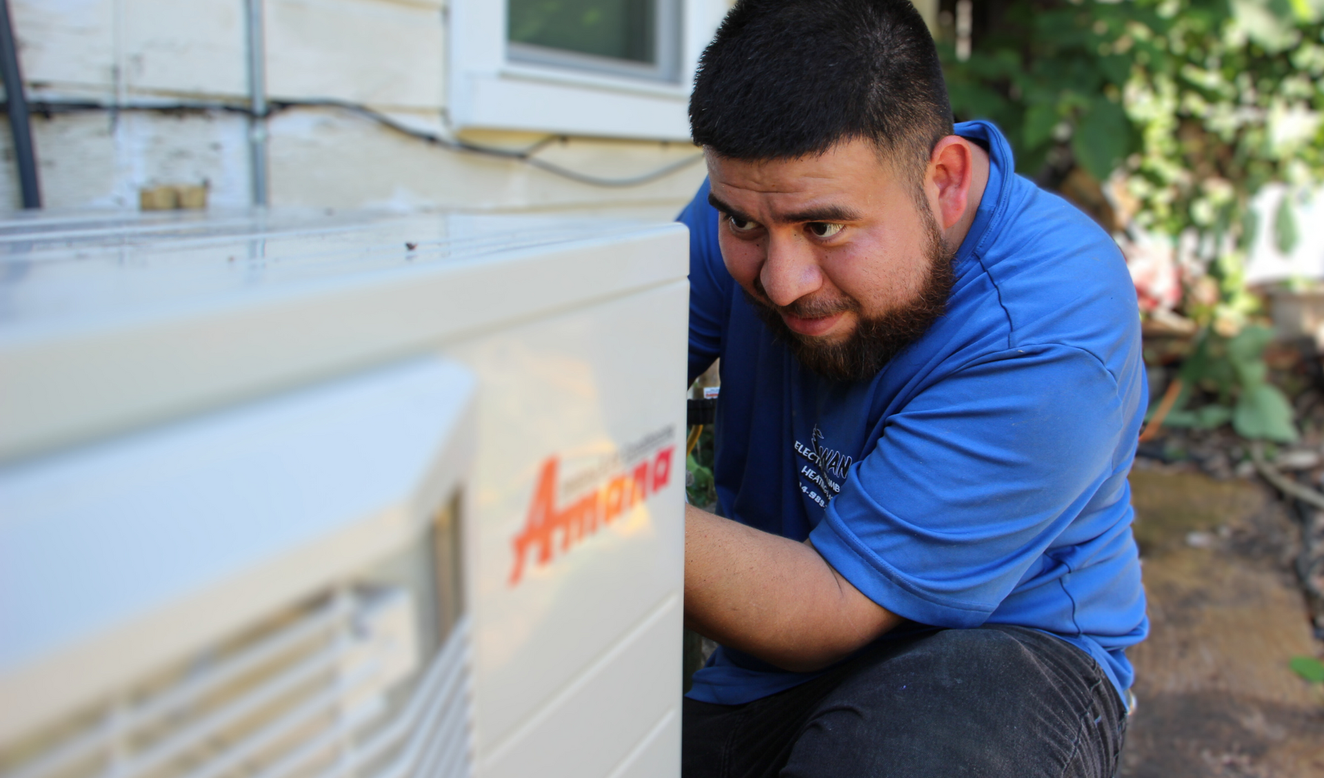 A man is working on an air conditioner outside of a house.