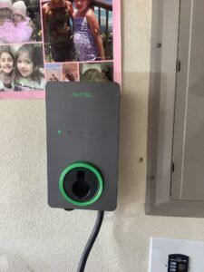 A charger is plugged into a wall next to a picture of a family.