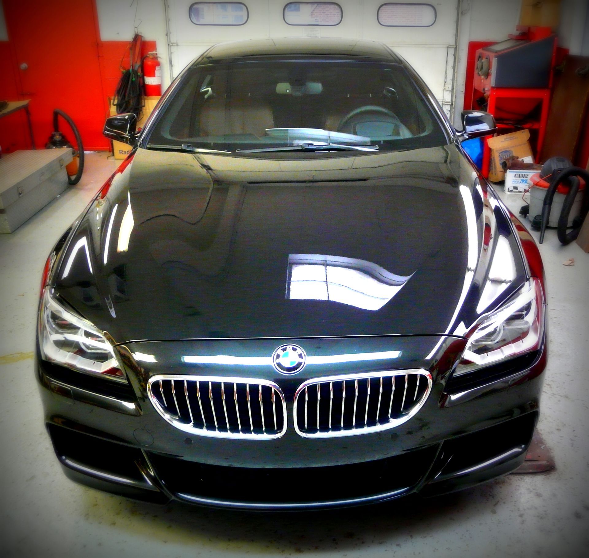 Black BMW coupe in a garage, with glossy finish.