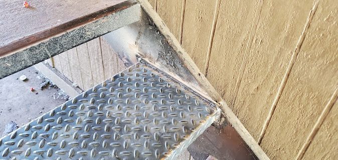 A close up of a metal staircase next to a wooden wall.