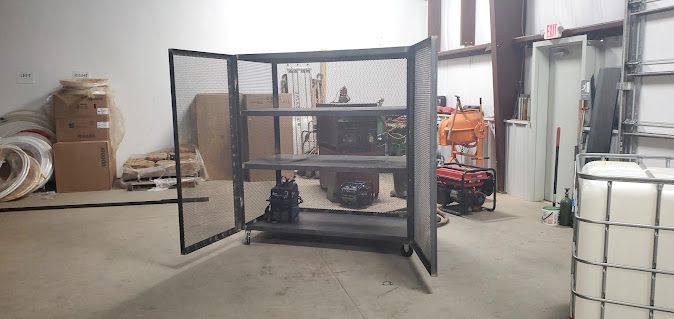 A metal cabinet is sitting in a warehouse with its doors open.