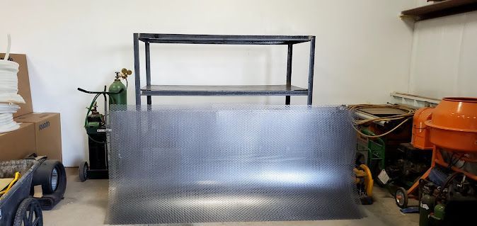 A large piece of metal is sitting in a garage next to a workbench.