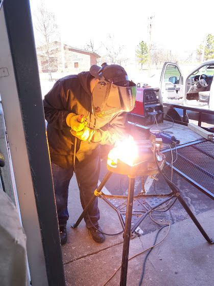 A man is welding a piece of metal in a garage.