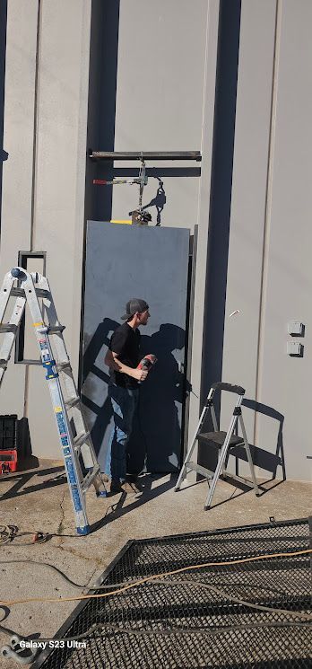 A man is standing in front of a building with a ladder.