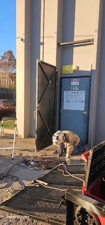 A dog is standing in front of a building with the door open.