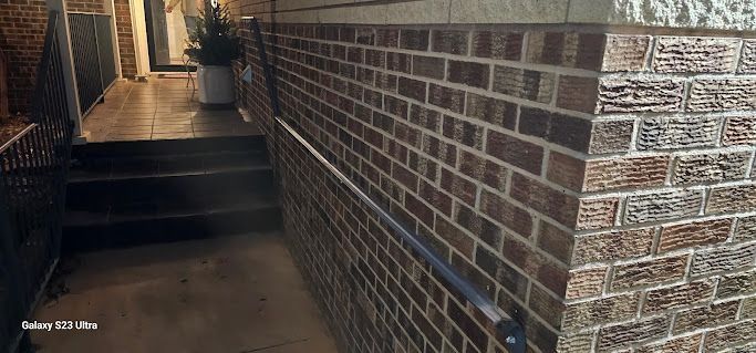 A brick wall with stairs leading up to it and a hand rail.