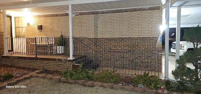 A brick house with a porch and a white roof at night.