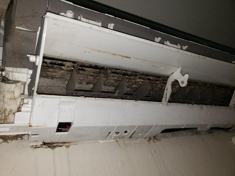 A close up of a dirty air conditioner on a wall.