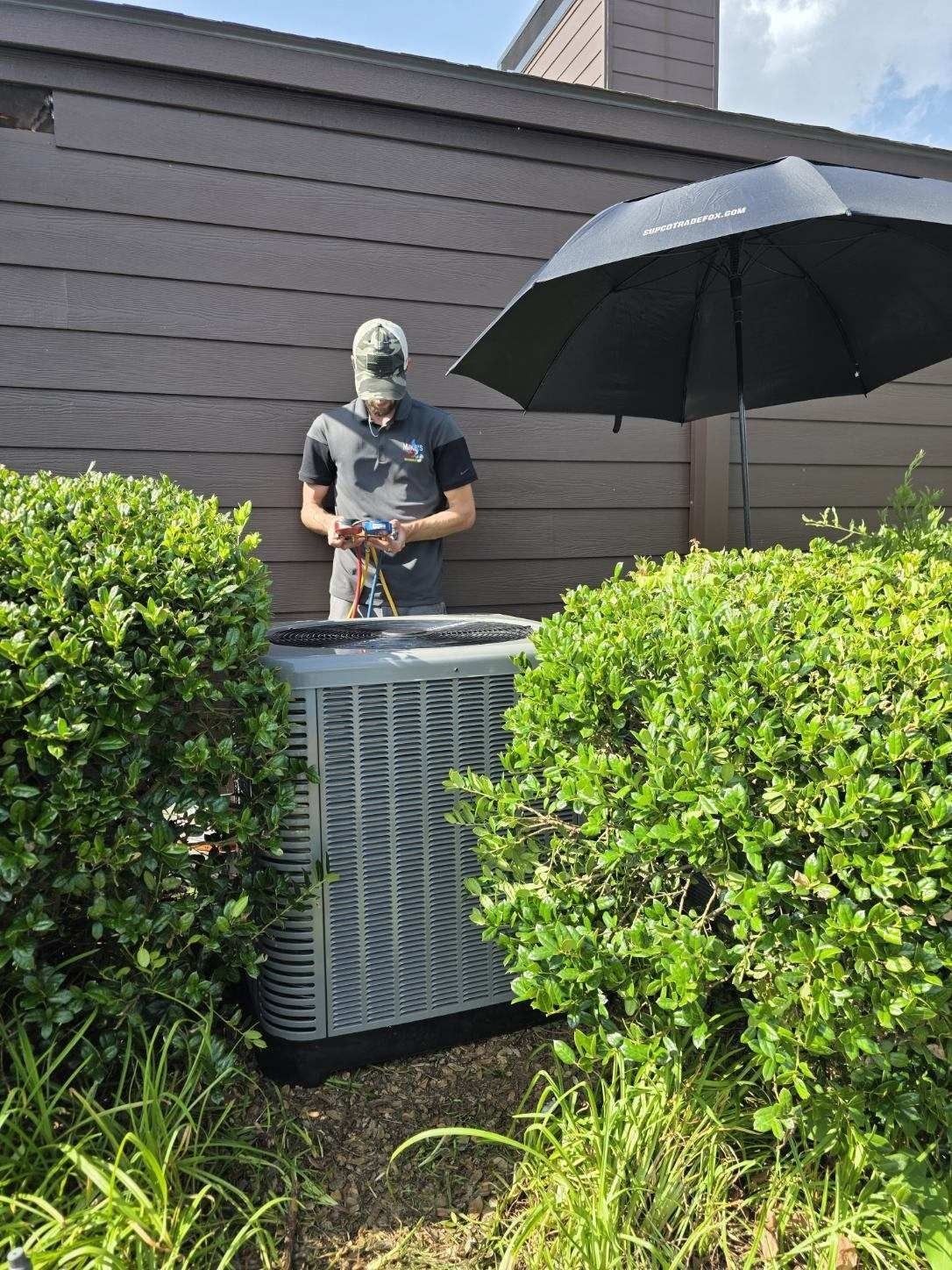 A man is working on a christmas tree outside of a building.