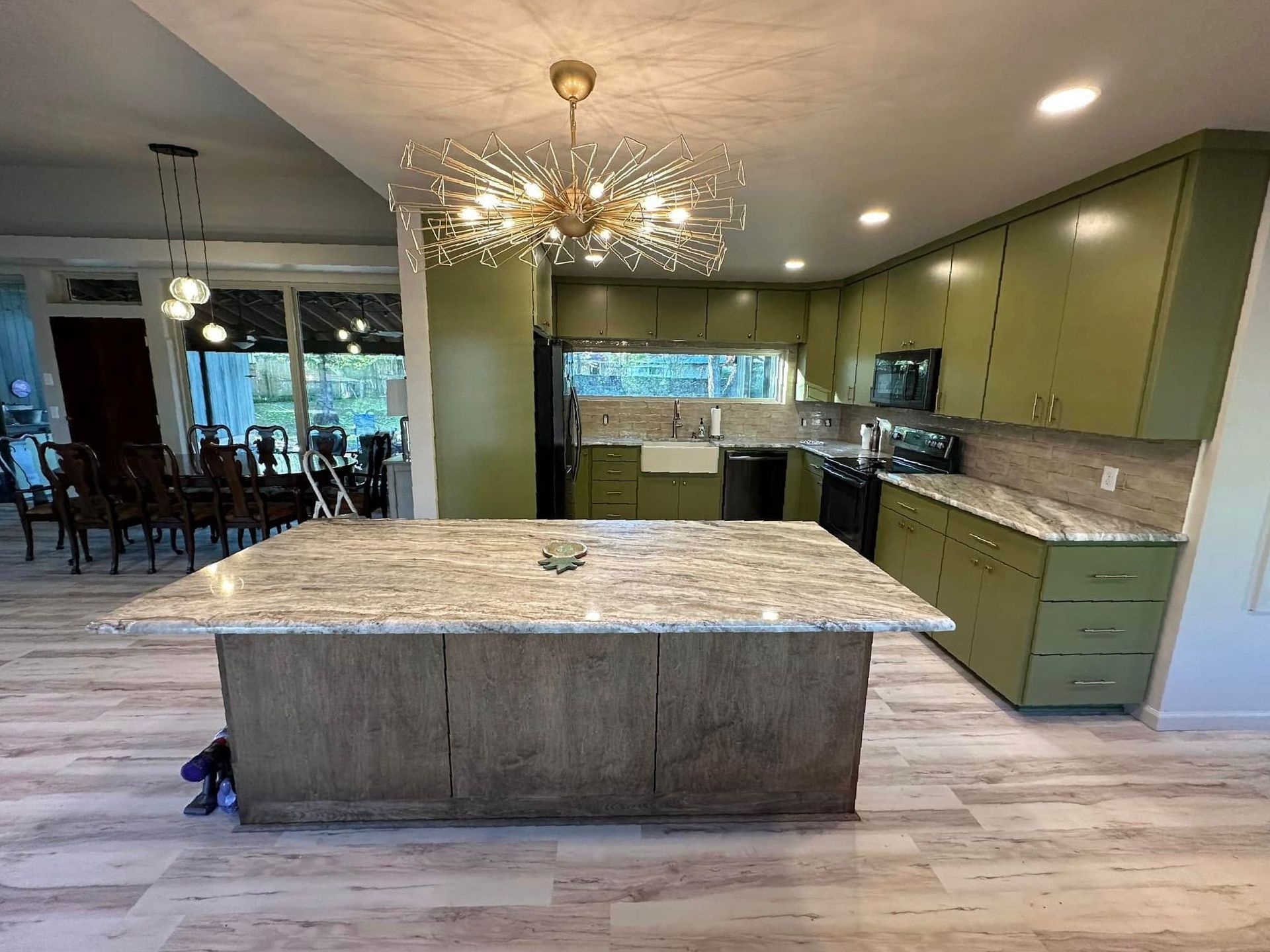 A kitchen with green cabinets and a large island in the middle.