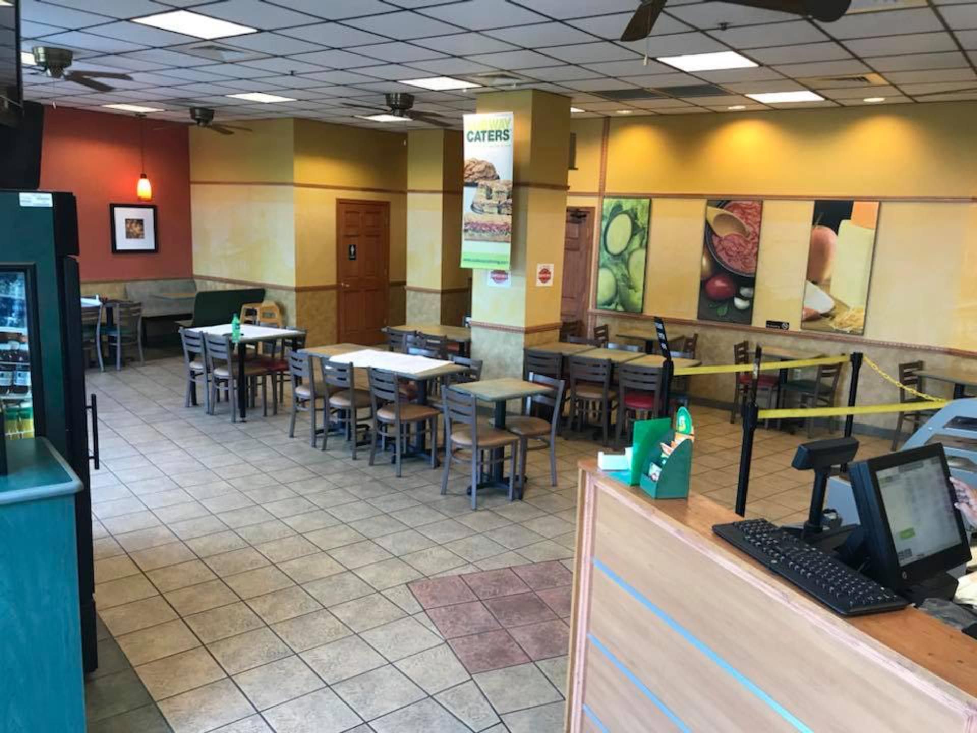 The inside of a subway restaurant with tables and chairs.
