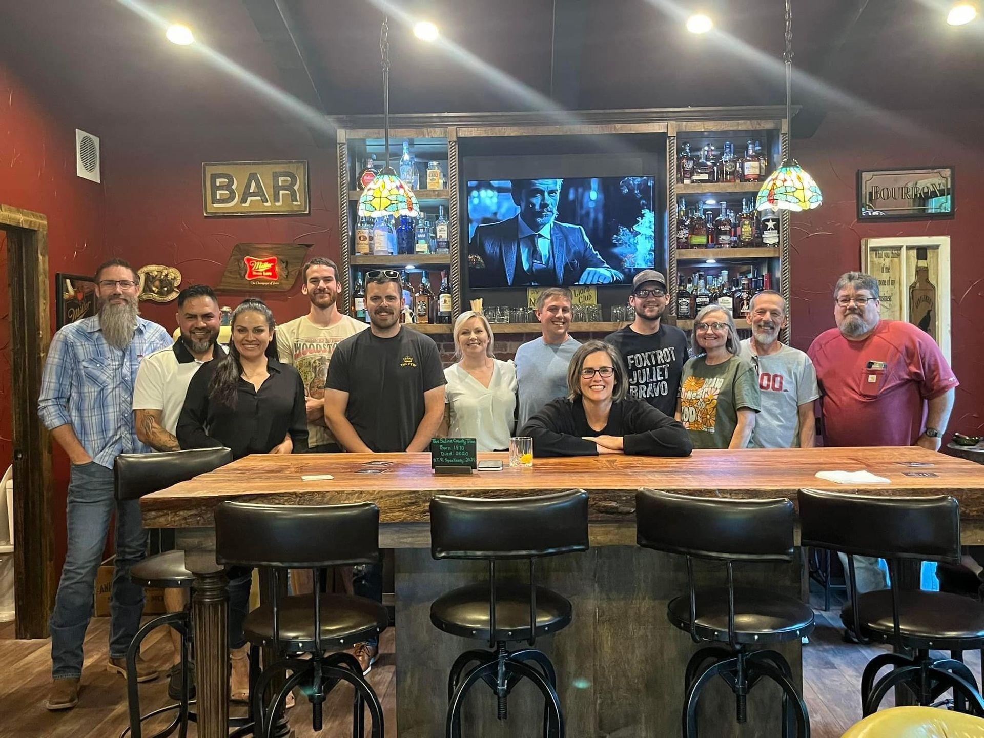 A group of people are posing for a picture in front of a bar.