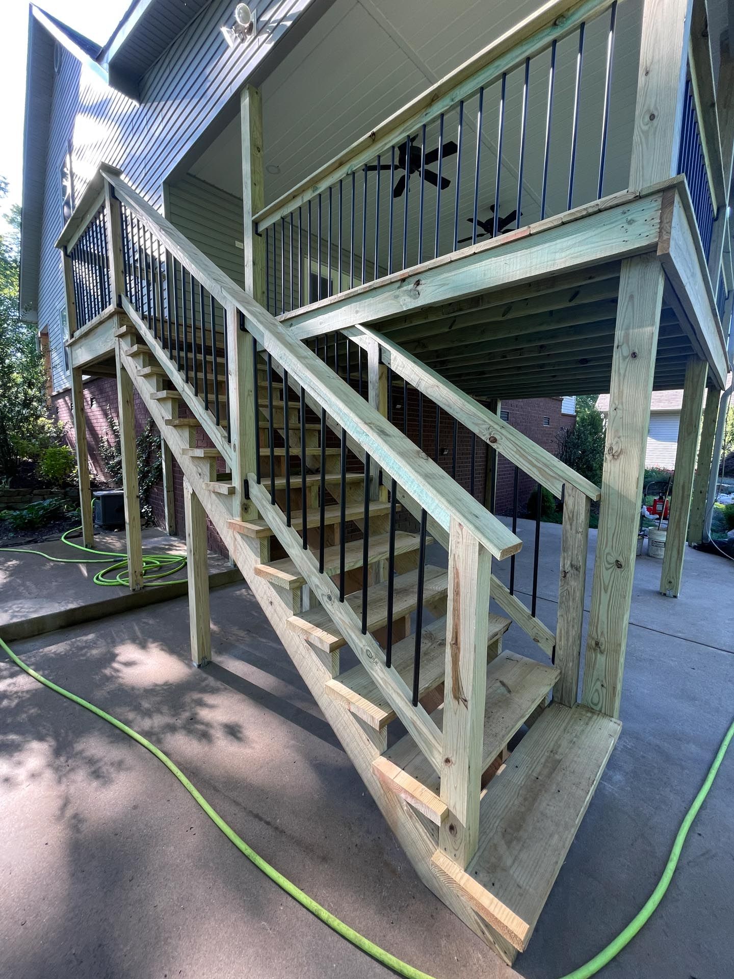 A wooden deck with stairs leading up to the second floor of a house.