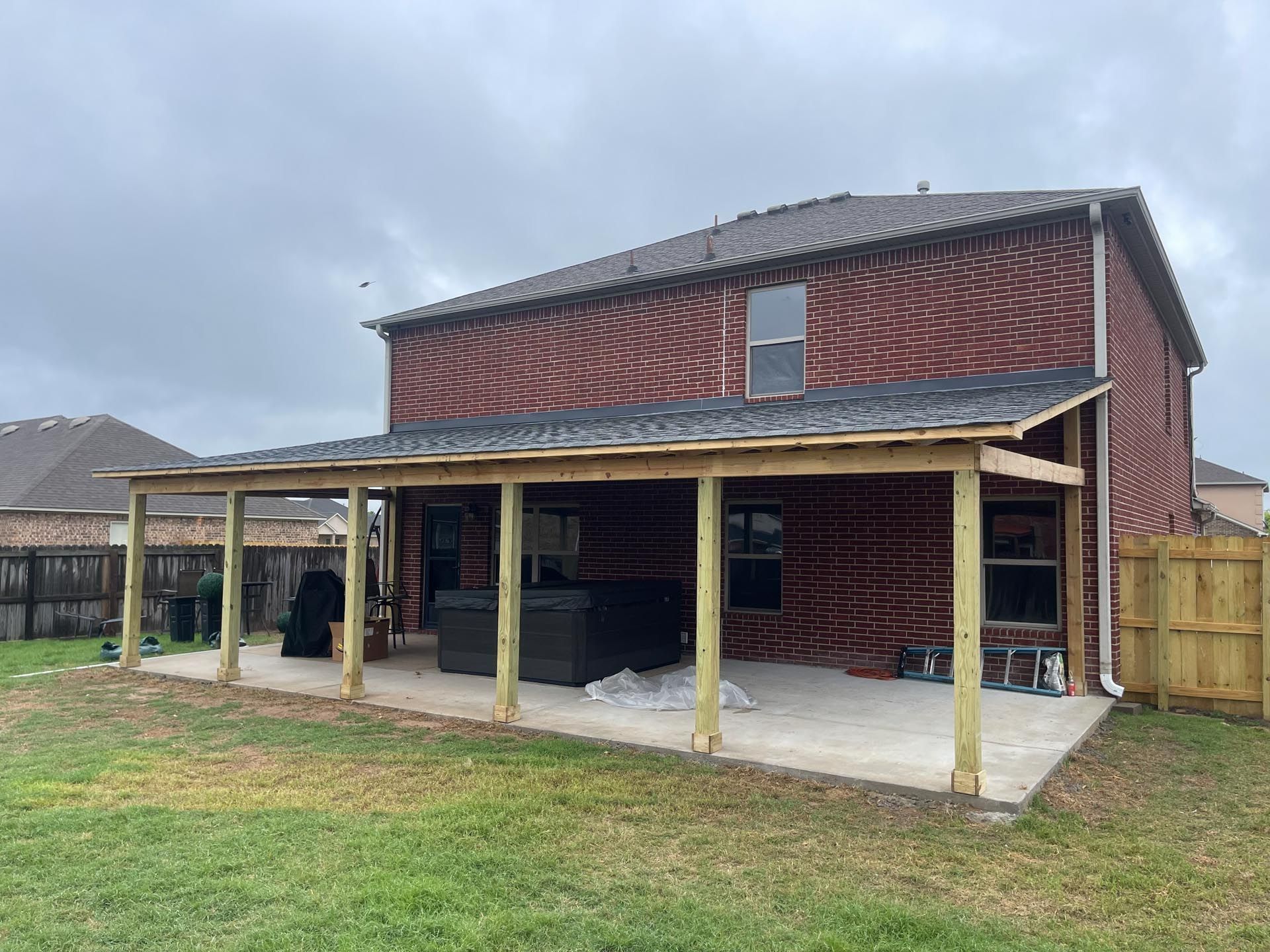 A brick house with a wooden porch in the backyard.