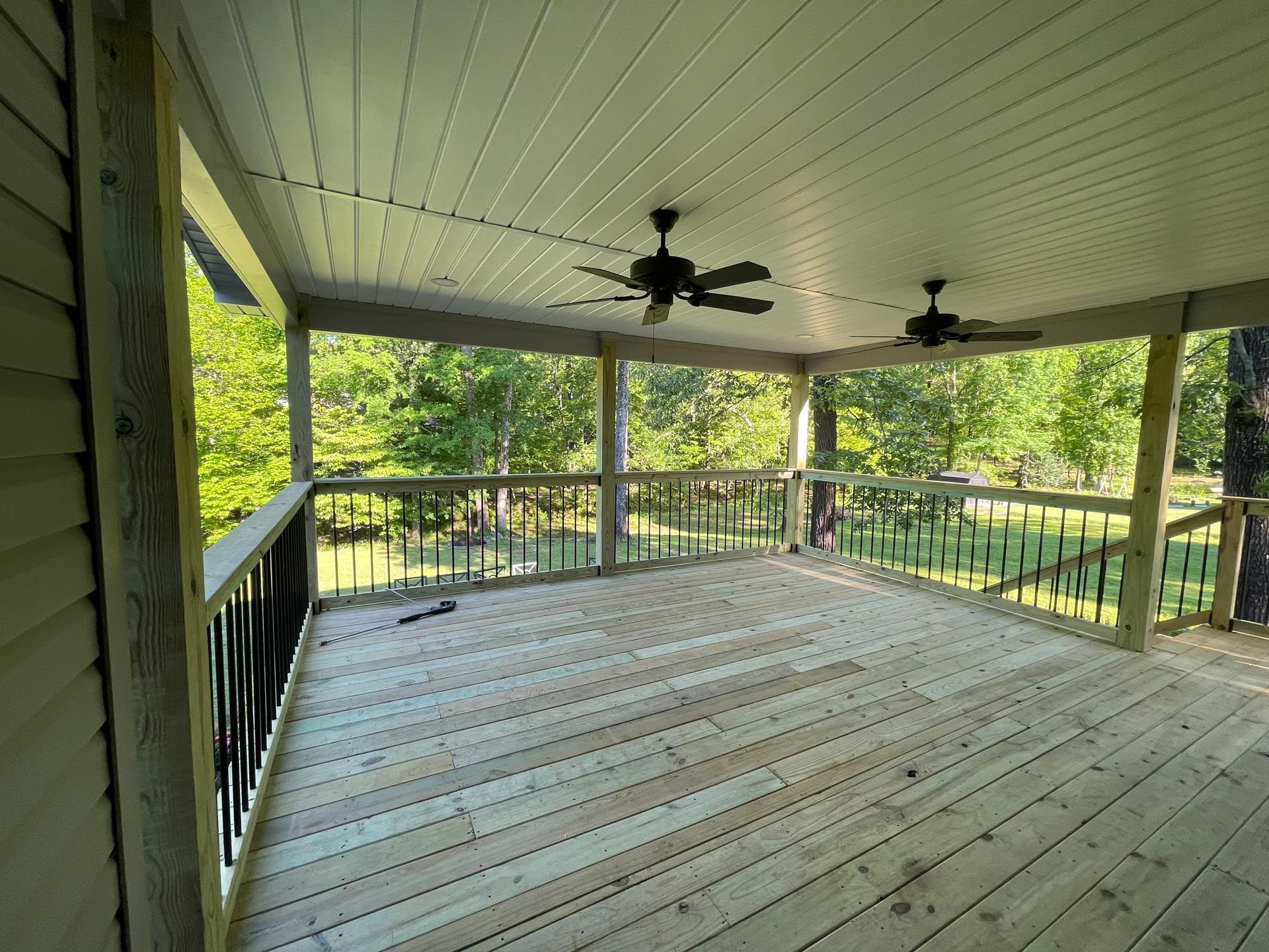 An empty screened in porch with a ceiling fan.