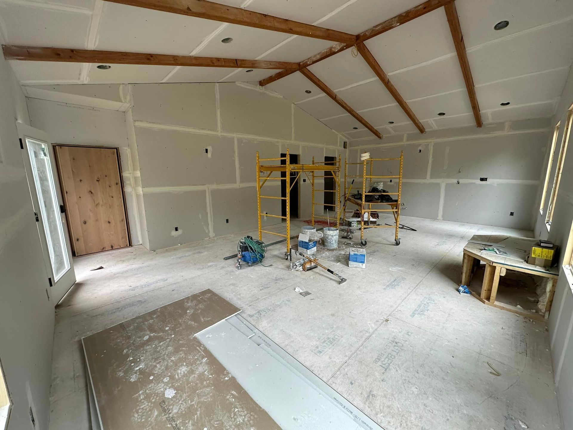 A large room with a scaffolding in the middle of it is being remodeled.