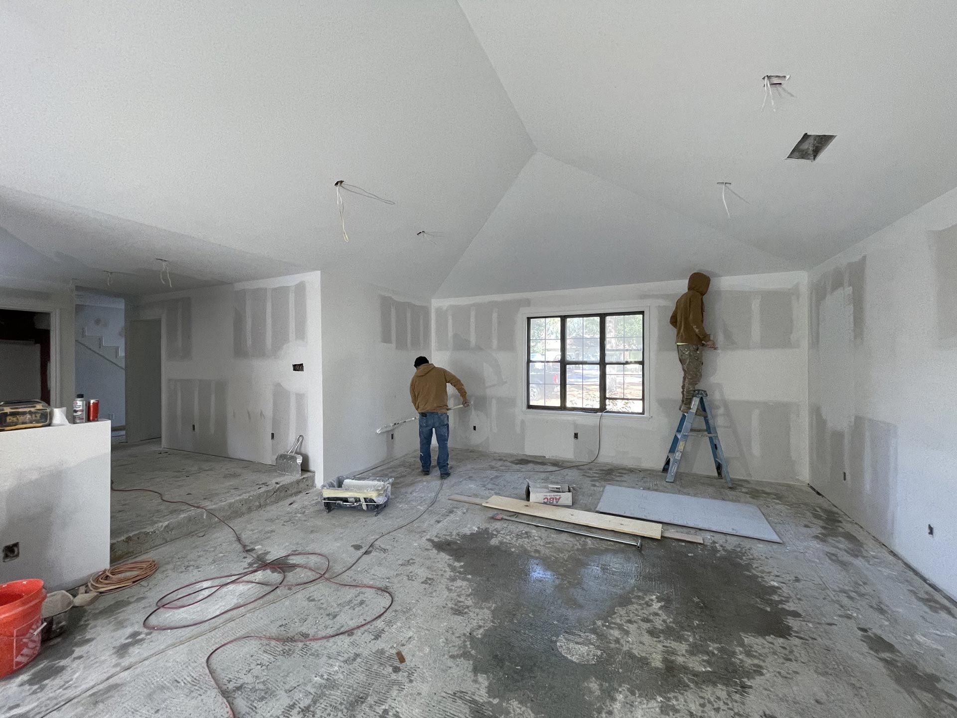 A man is standing on a ladder in an empty room.
