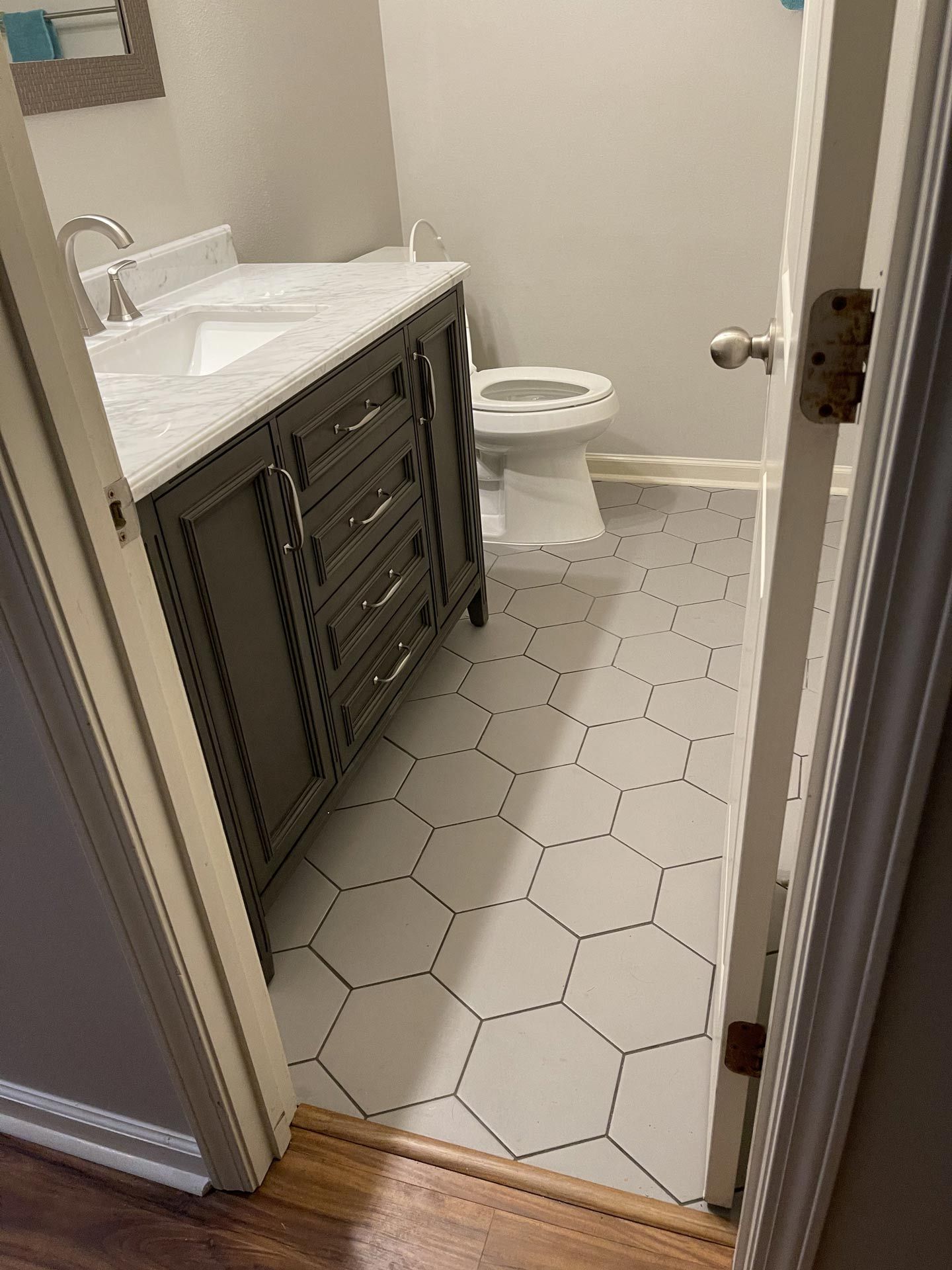 A bathroom with a sink , toilet , and hexagonal tile floor.
