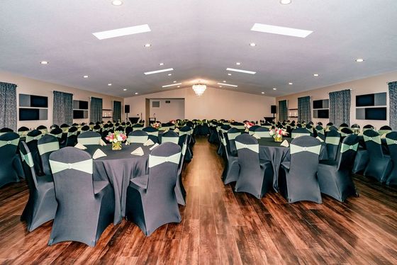 A large room with tables and chairs set up for a wedding reception.