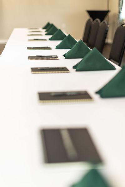 A long white table with green napkins on it