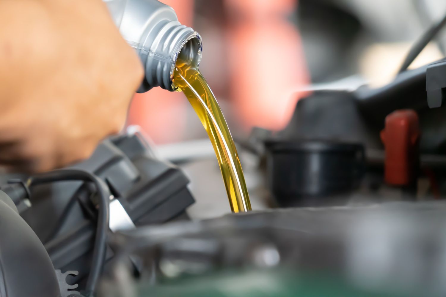 A person is pouring oil into a car engine.