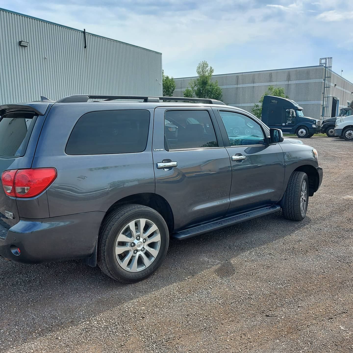 A gray suv is parked in a gravel lot in front of a building.