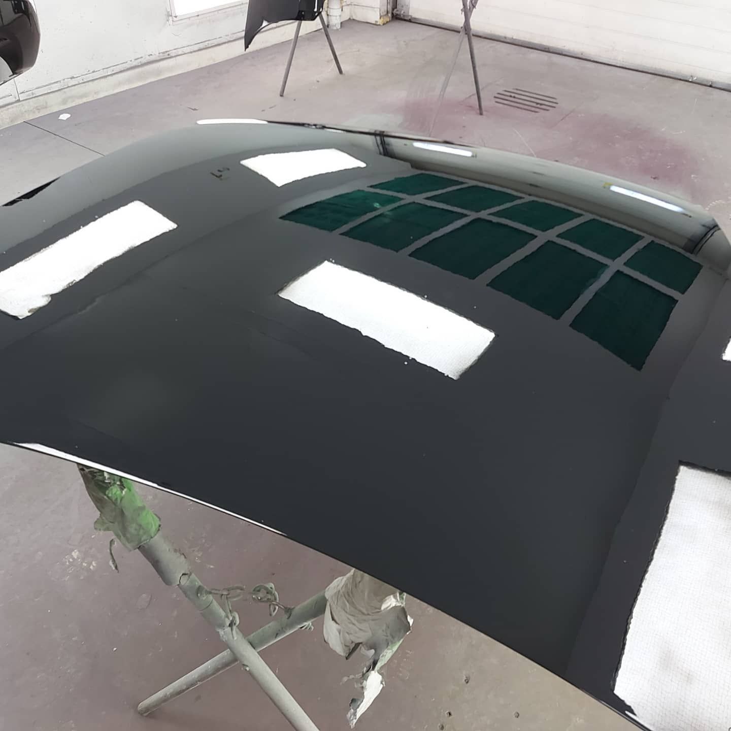 A black car hood is sitting on a stand in a garage