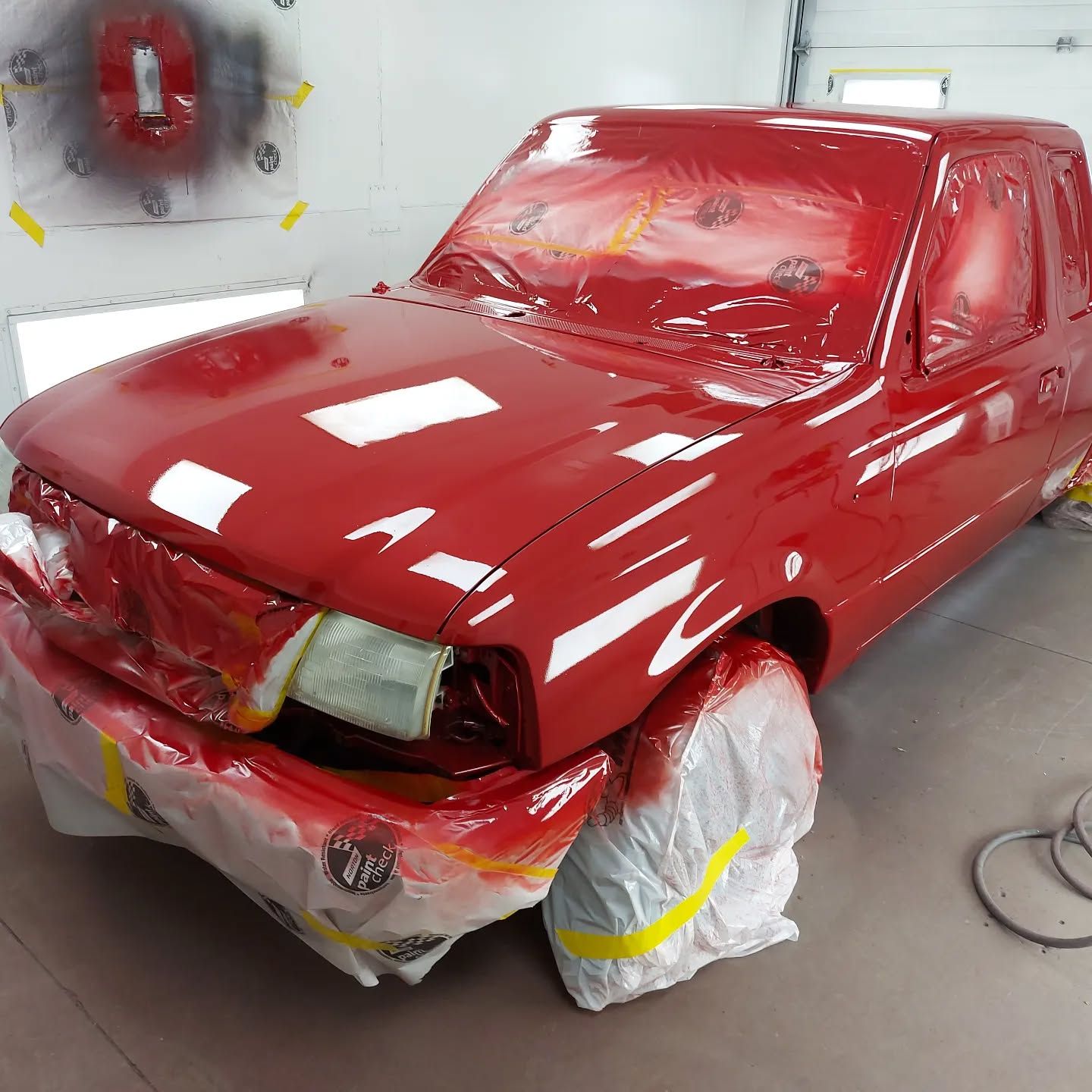 A red truck is being painted in a garage