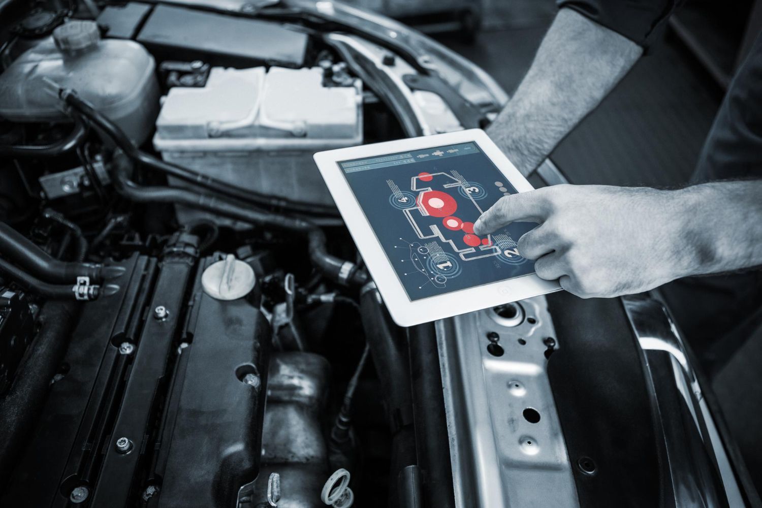 Person using a tablet to diagnose a car engine in a garage