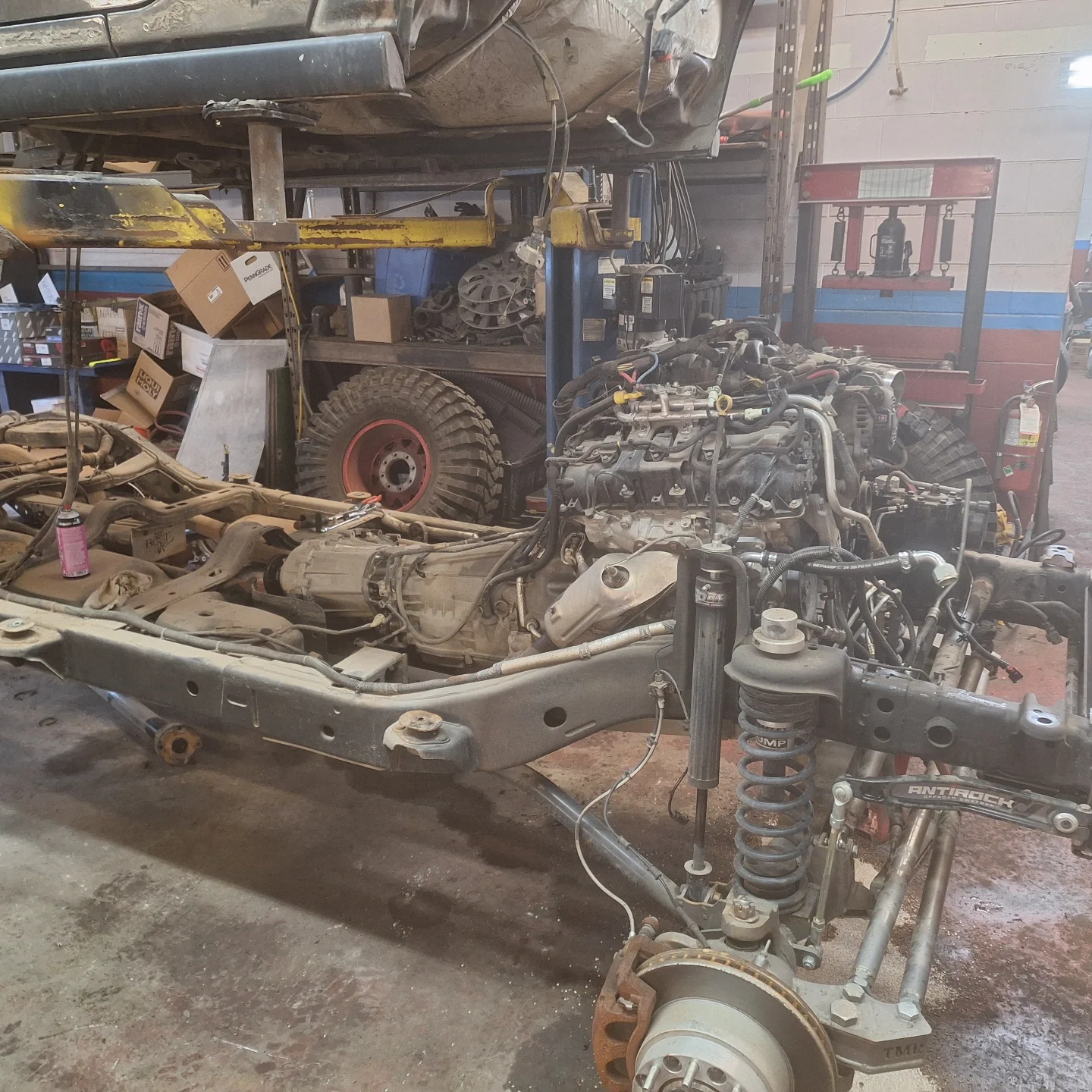 A red truck is being painted in a garage