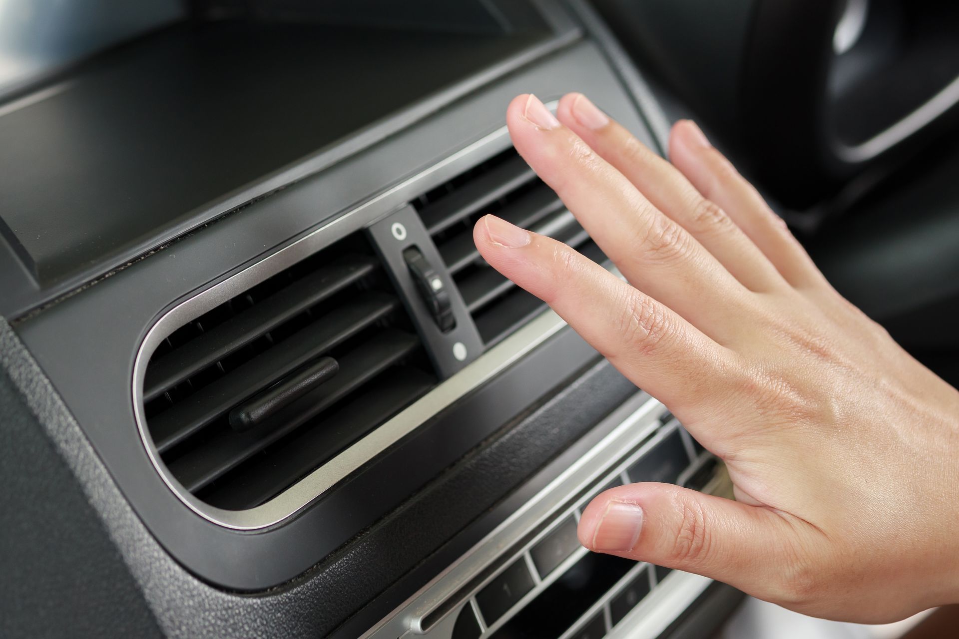 A person is adjusting the air conditioner in a car.