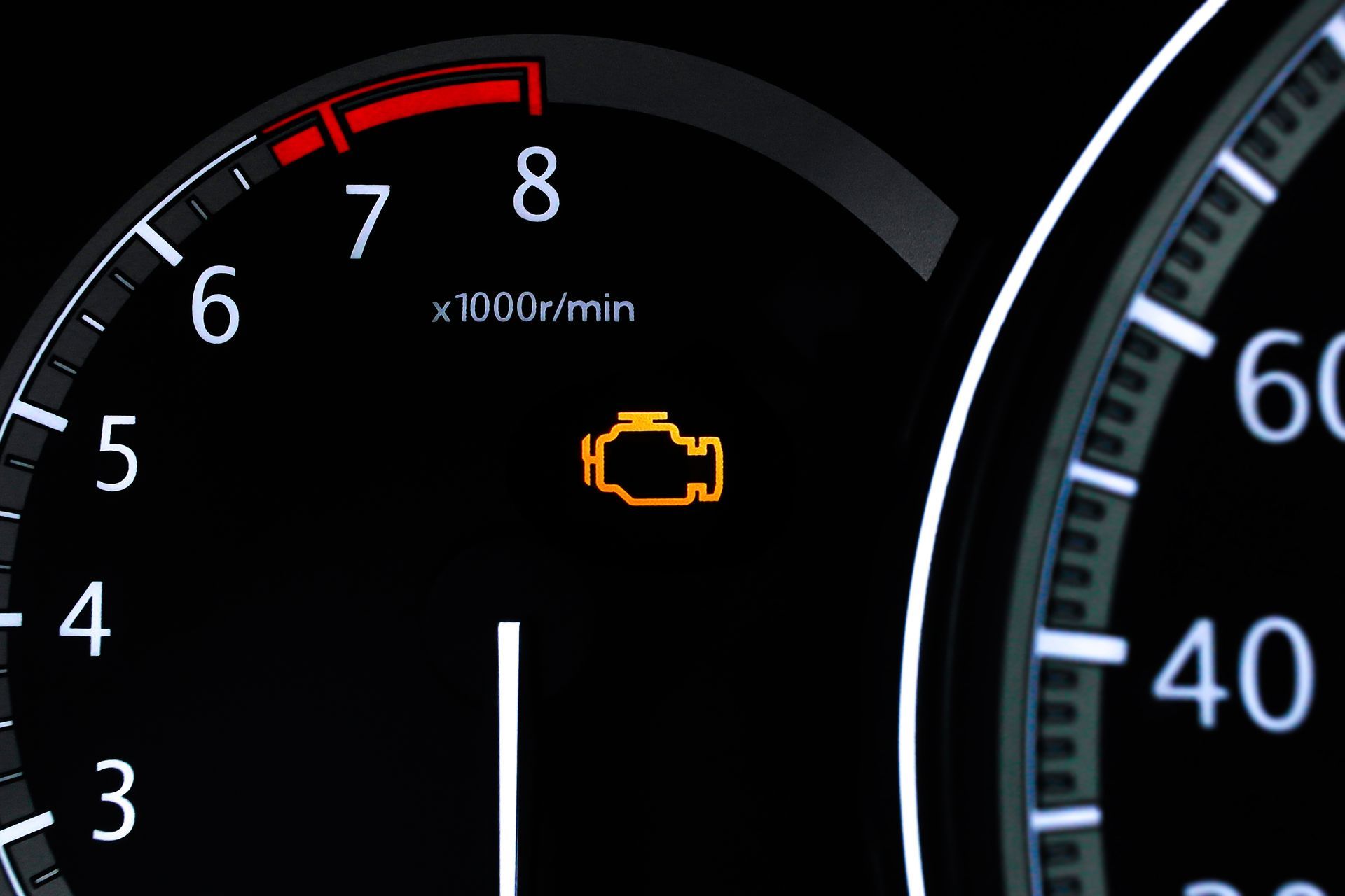 Car dashboard with check engine light illuminated. Tachometer reading 7,000 RPM. Speedometer partially visible.