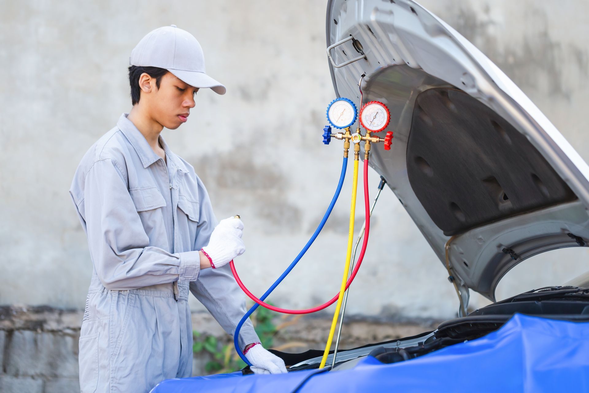 A man is working on a car with the hood open.