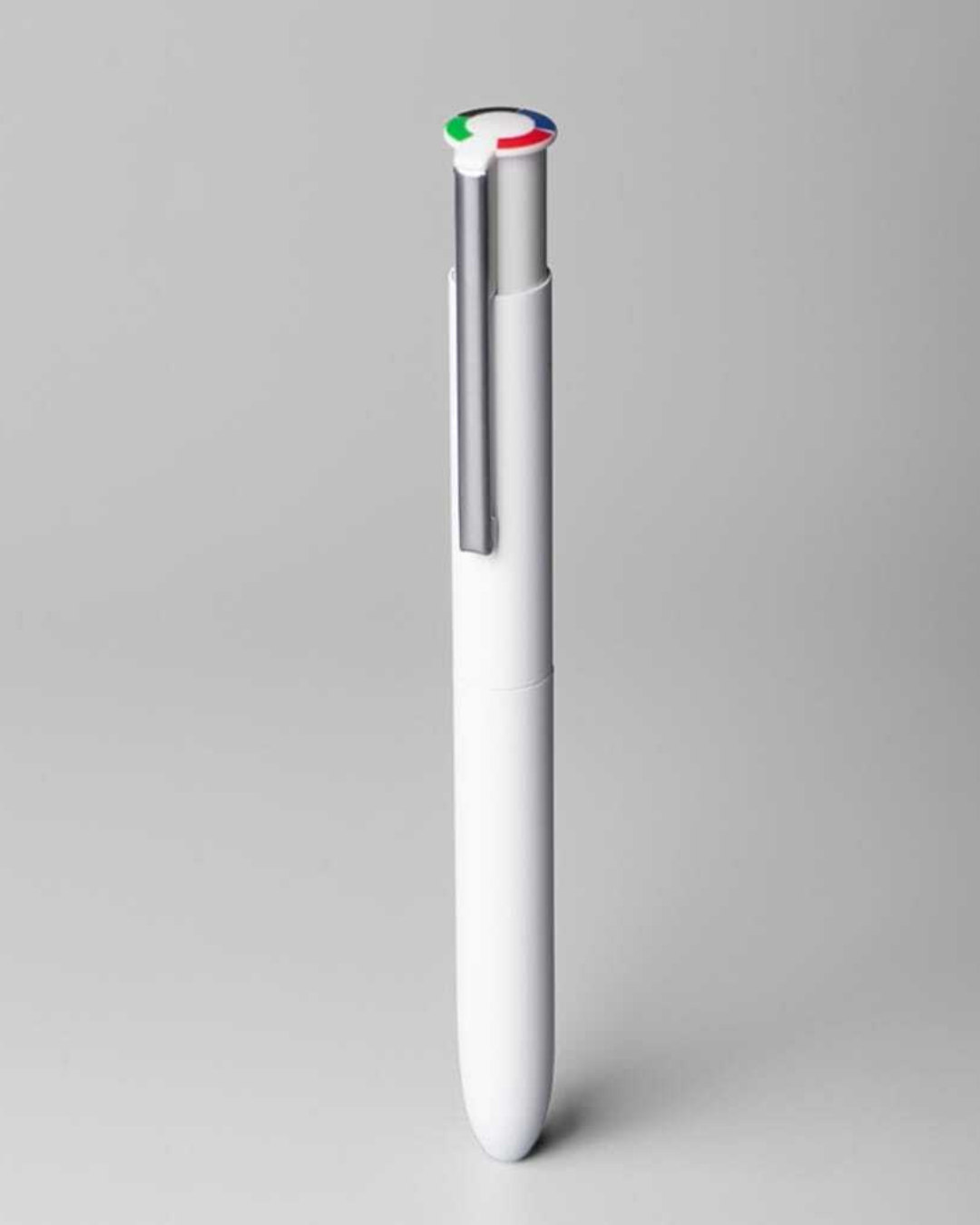 Un stylo rétractable blanc avec un clip argenté et un bouton supérieur orné de segments de couleur verte, rouge et bleue.